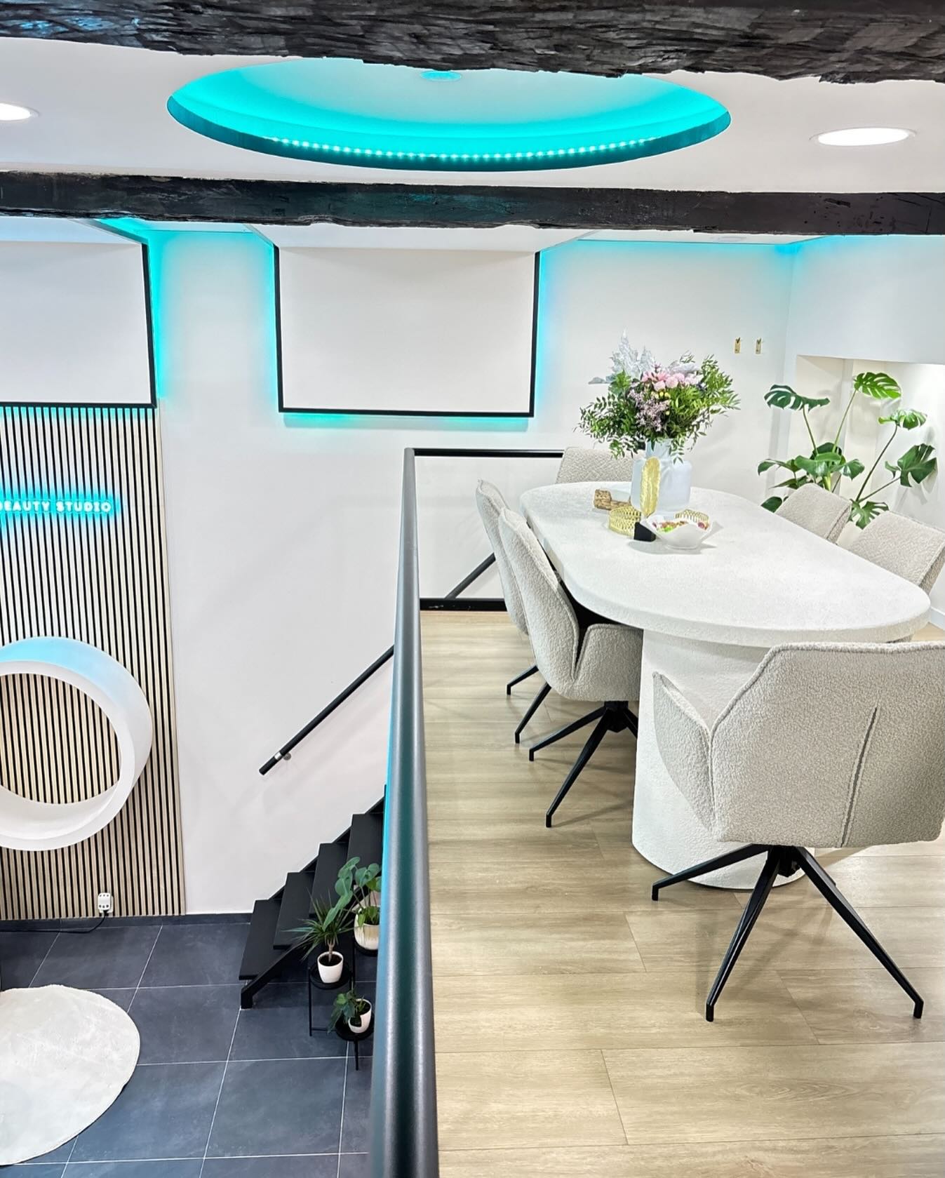 De studio: een witte ovale tafel met stoelen, een lichtring in het plafond en de neonletters Beauty Studio aan de wand